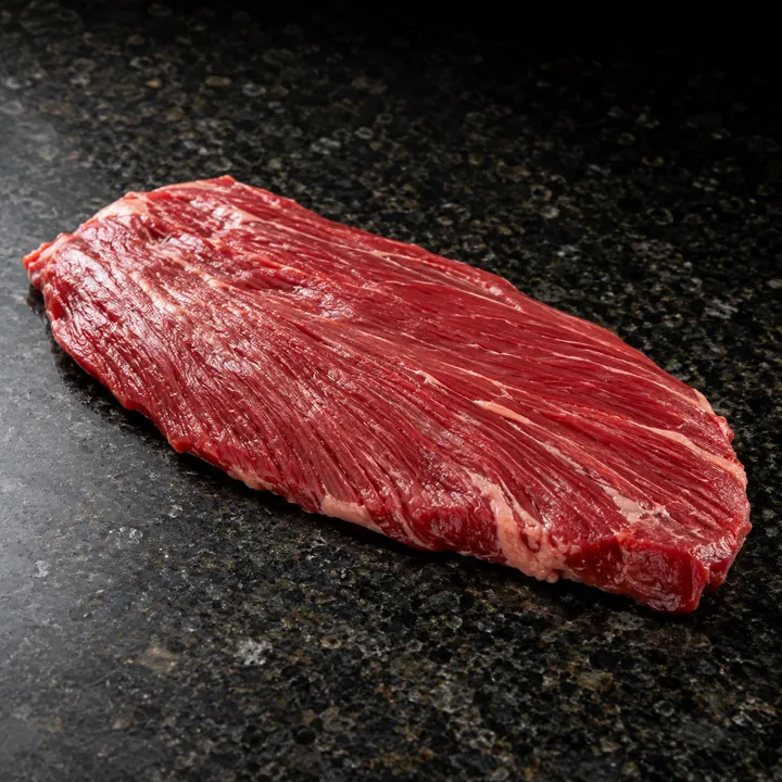 A raw flank steak on dark granite.
